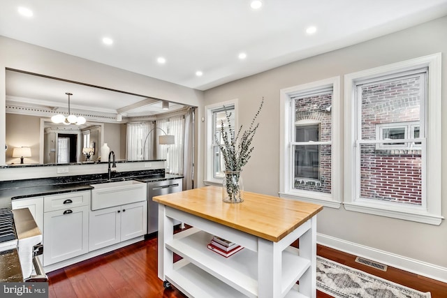 kitchen featuring visible vents, dishwasher, dark countertops, hanging light fixtures, and white cabinetry