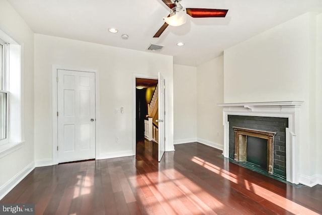 unfurnished living room with dark wood-type flooring, a fireplace with flush hearth, visible vents, and baseboards