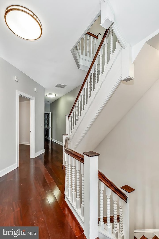 stairway with wood finished floors, visible vents, and baseboards