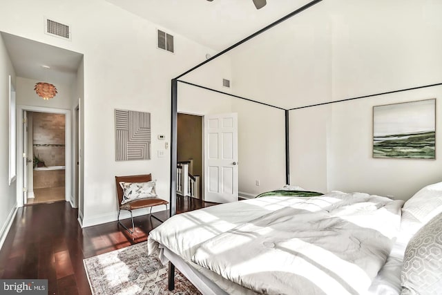 bedroom featuring dark wood-type flooring, ceiling fan, ensuite bathroom, and a towering ceiling