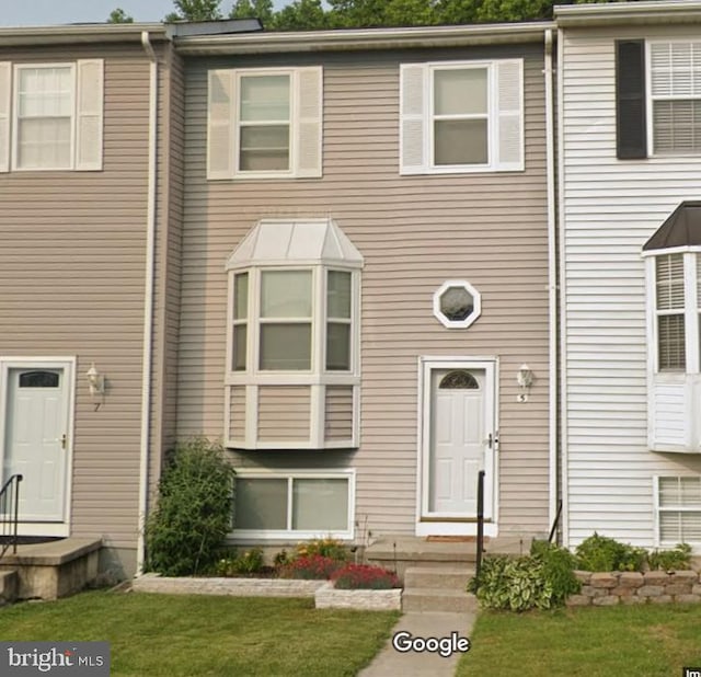 view of property featuring entry steps and a front lawn