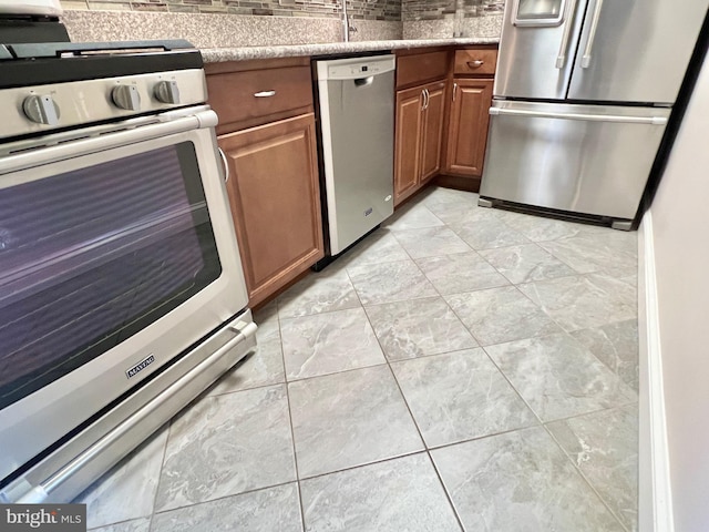 490 M St SW Unit W304, Washington, DC 20024 - kitchen with stainless steel appliances, brown cabinetry, light tile patterned floors, and light stone counters