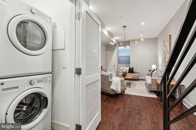 clothes washing area featuring dark hardwood / wood-style flooring and stacked washer / drying machine