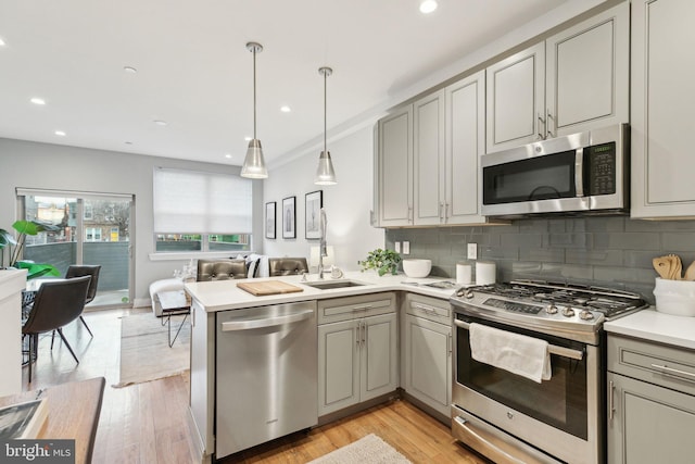 kitchen with appliances with stainless steel finishes, decorative light fixtures, sink, and decorative backsplash