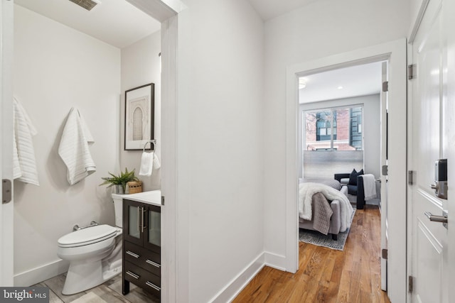 bathroom with vanity, toilet, and hardwood / wood-style floors