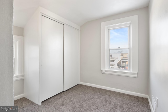 unfurnished bedroom featuring light colored carpet, vaulted ceiling, and a closet