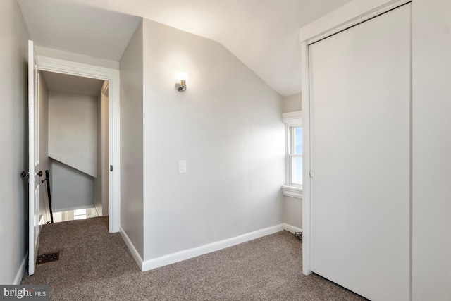 corridor featuring vaulted ceiling and carpet flooring