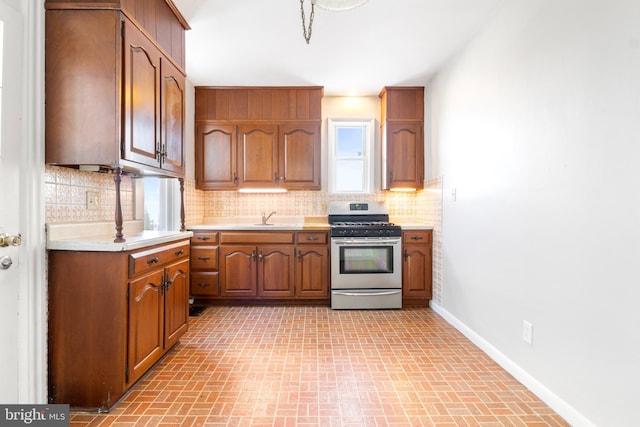 kitchen featuring stainless steel gas range, sink, and backsplash