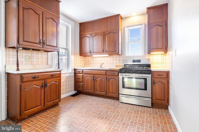 kitchen featuring sink, stainless steel range with gas stovetop, and decorative backsplash