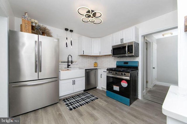 kitchen featuring hanging light fixtures, appliances with stainless steel finishes, sink, and white cabinets