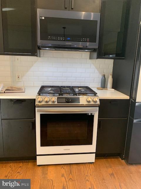 kitchen featuring backsplash, light wood-type flooring, and appliances with stainless steel finishes