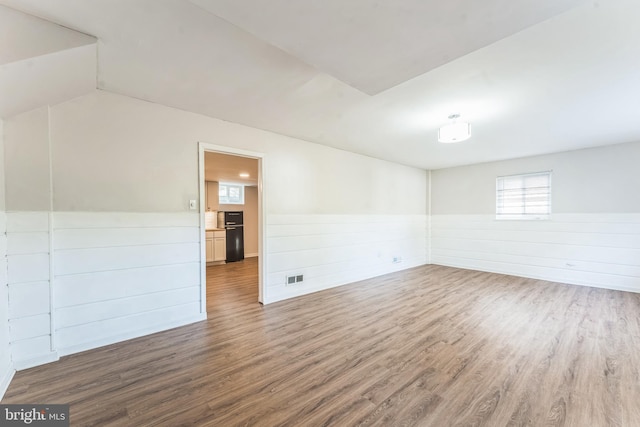 unfurnished room with hardwood / wood-style flooring and vaulted ceiling