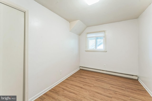 additional living space with a baseboard heating unit and light wood-type flooring