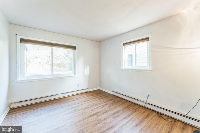 unfurnished room featuring a baseboard heating unit and light wood-type flooring