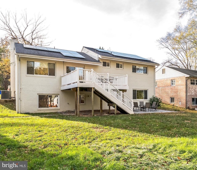 back of property with central AC, a patio area, solar panels, a yard, and a deck