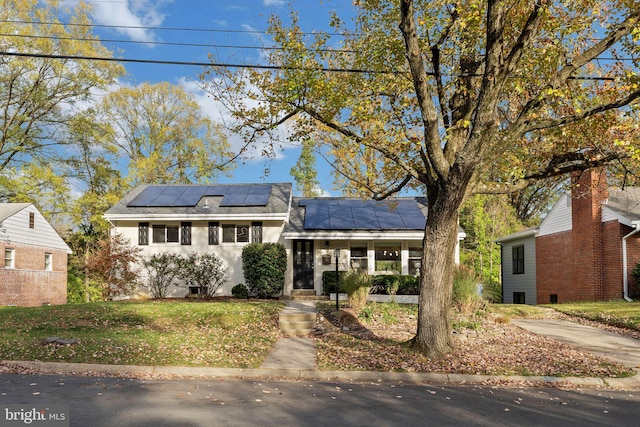 view of front facade with a porch, a front lawn, and solar panels