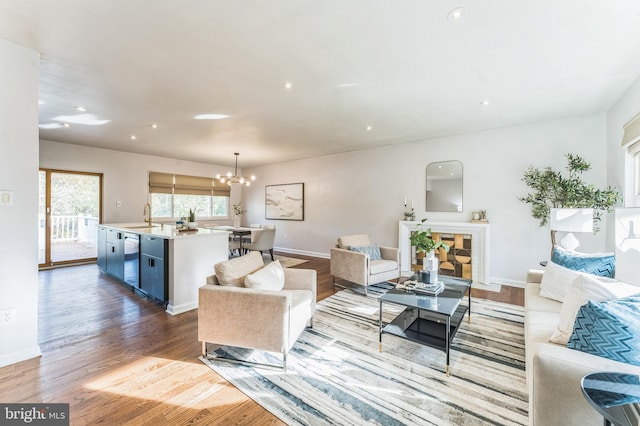 living room with hardwood / wood-style flooring, sink, and a notable chandelier