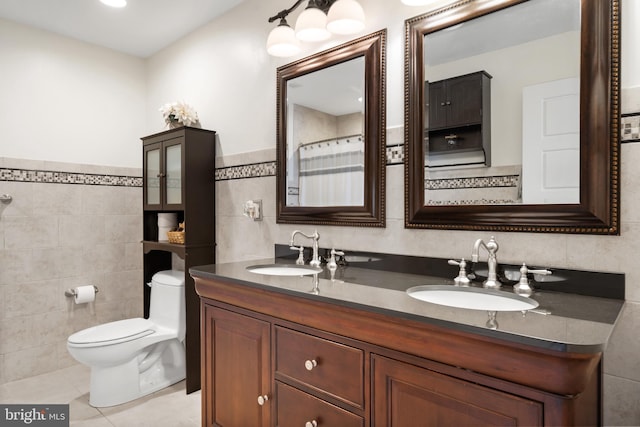 bathroom with double vanity, tile patterned flooring, a sink, and tile walls