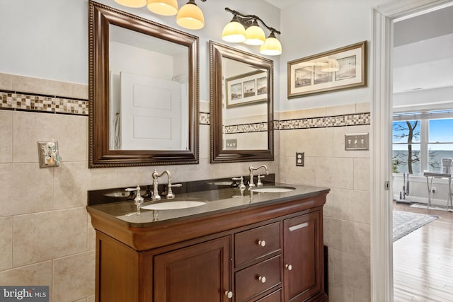 bathroom featuring double vanity, a sink, and tile walls