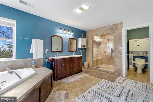 bathroom featuring toilet, a sink, visible vents, a shower stall, and double vanity