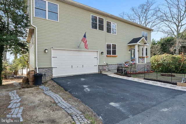 view of front of property featuring driveway, stone siding, and an attached garage