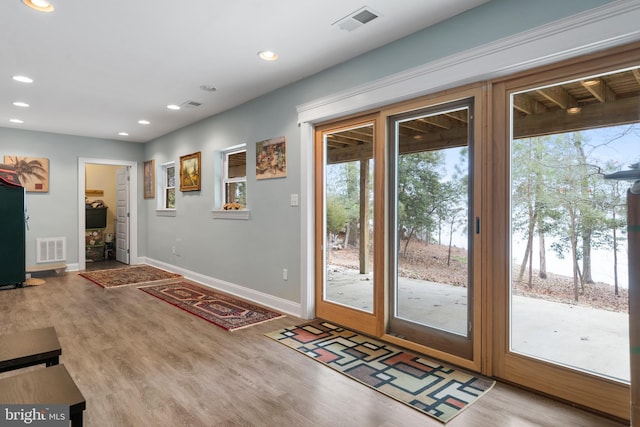 doorway to outside featuring wood finished floors, visible vents, and baseboards