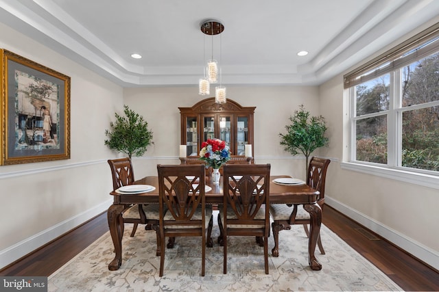 dining area featuring recessed lighting, a raised ceiling, baseboards, and wood finished floors