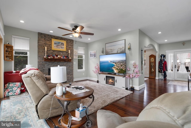 living room with arched walkways, a fireplace, dark wood-style floors, and recessed lighting