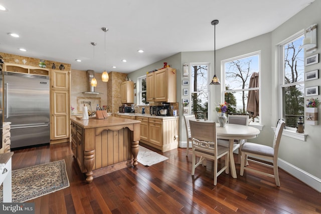 kitchen with built in refrigerator, light countertops, and decorative light fixtures