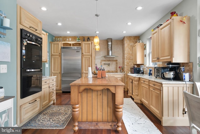 kitchen featuring stainless steel built in fridge, hanging light fixtures, wall chimney range hood, and light brown cabinetry