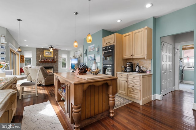 kitchen featuring a large fireplace, pendant lighting, light countertops, and open floor plan