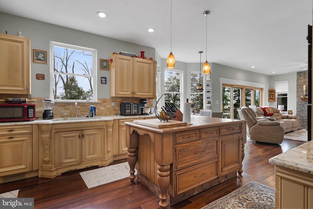 kitchen with dark wood-type flooring, open floor plan, a sink, and hanging light fixtures