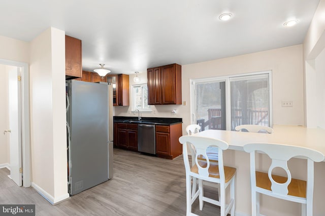 kitchen with a breakfast bar, appliances with stainless steel finishes, light hardwood / wood-style floors, and sink