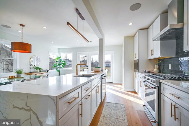 kitchen with pendant lighting, sink, stainless steel range with gas cooktop, and wall chimney exhaust hood