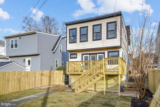 rear view of house with a wooden deck and a lawn