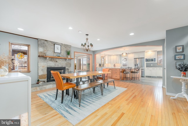 dining room featuring a fireplace, a notable chandelier, and light hardwood / wood-style flooring