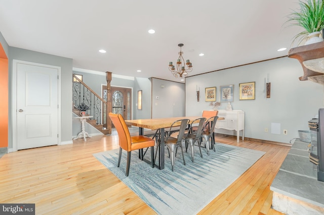 dining area featuring an inviting chandelier, crown molding, light hardwood / wood-style flooring, and a wood stove