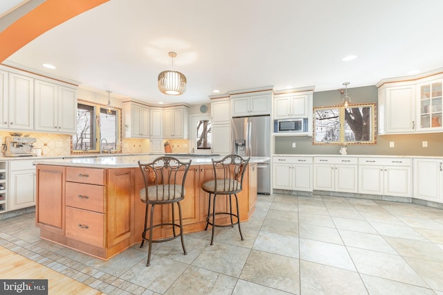 kitchen with hanging light fixtures, stainless steel appliances, a center island, and a breakfast bar