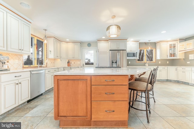 kitchen with hanging light fixtures, a kitchen bar, stainless steel appliances, and a kitchen island