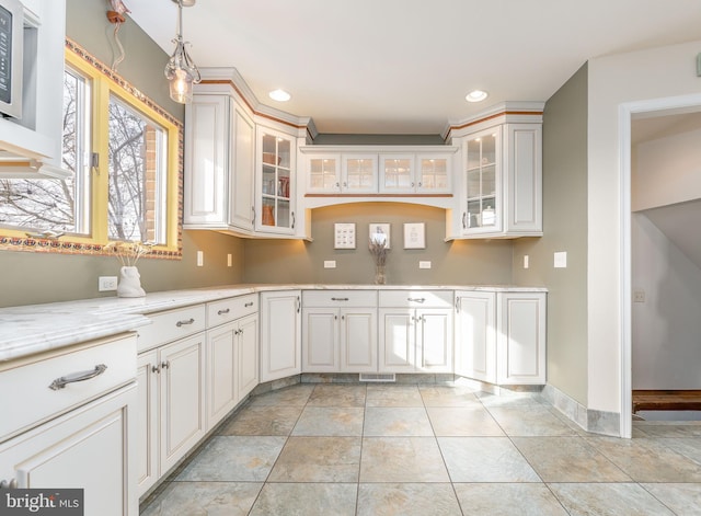 kitchen featuring light tile patterned flooring, pendant lighting, white cabinets, and light stone counters