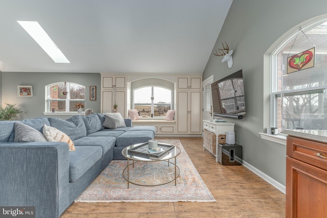 living room with lofted ceiling with skylight and light hardwood / wood-style flooring