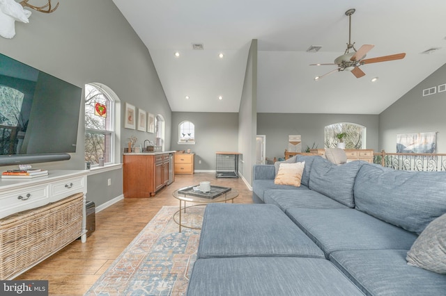 living room with sink, a wealth of natural light, high vaulted ceiling, and light hardwood / wood-style flooring