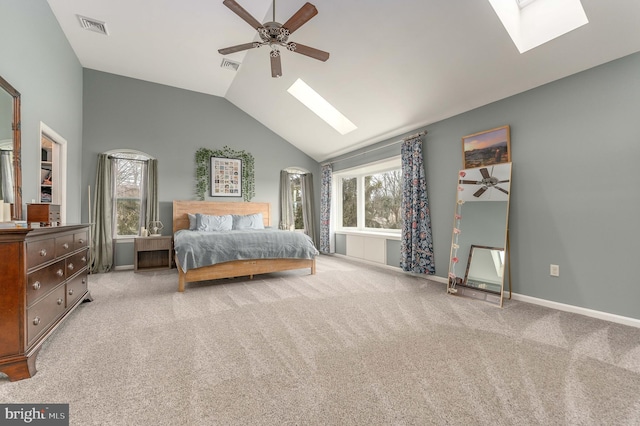 bedroom featuring multiple windows, ceiling fan, light carpet, and vaulted ceiling with skylight