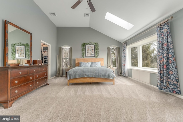 carpeted bedroom featuring vaulted ceiling with skylight and ceiling fan