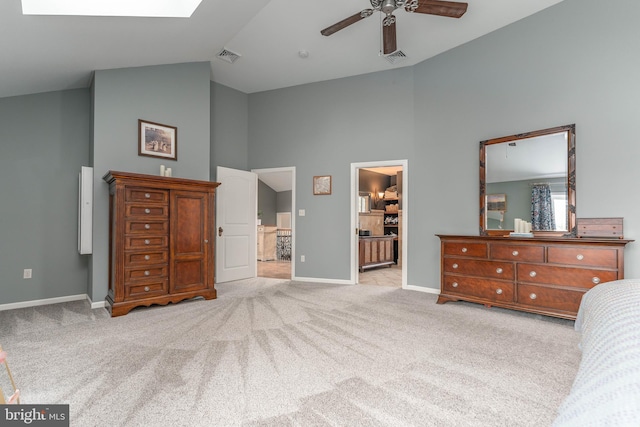 carpeted bedroom with connected bathroom, high vaulted ceiling, a skylight, a walk in closet, and ceiling fan