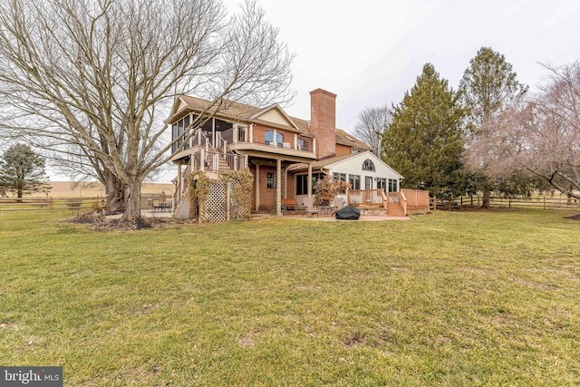 rear view of house featuring a wooden deck and a lawn