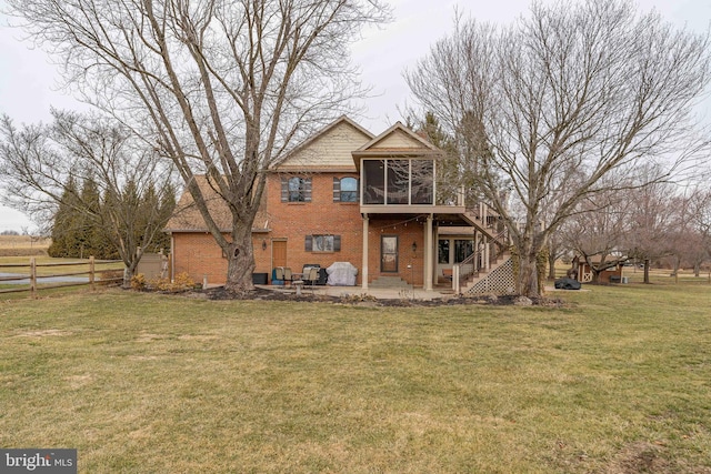 rear view of house with a patio, a deck, a sunroom, and a lawn