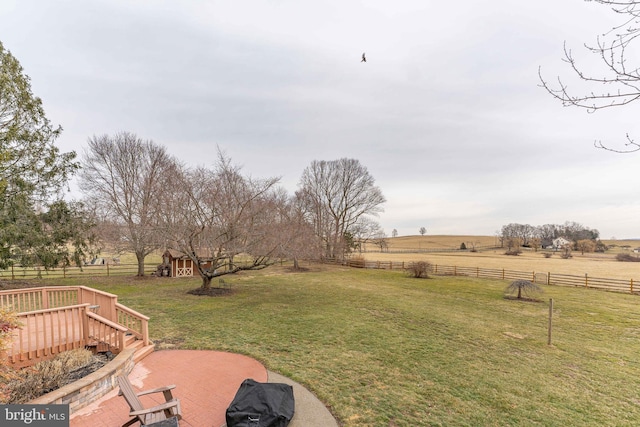 view of yard with a deck, a shed, and a rural view