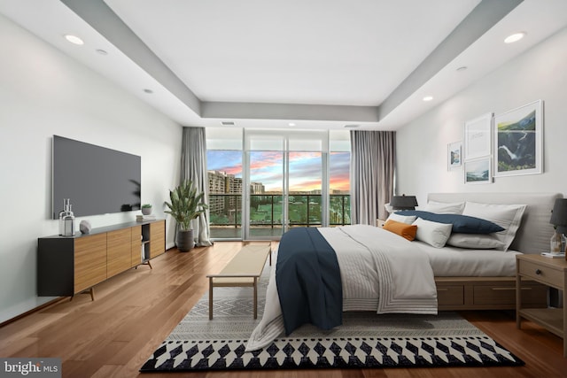 bedroom featuring access to exterior, hardwood / wood-style flooring, and floor to ceiling windows