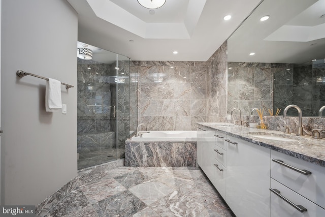 bathroom with vanity, shower with separate bathtub, tile walls, and a tray ceiling